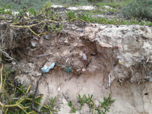 a close up of the eroding beach that shows the layers of garbage